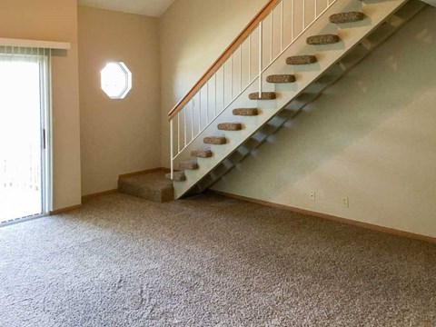 a living room with a staircase leading up to the loft