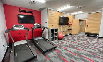 a 24-hour fitness center with treadmills, TVs, and yoga equipment.