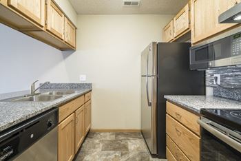 A kitchen with wooden cabinets and granite countertops.