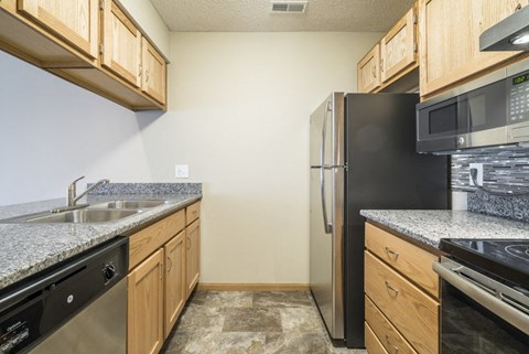 A kitchen with wooden cabinets and granite countertops.