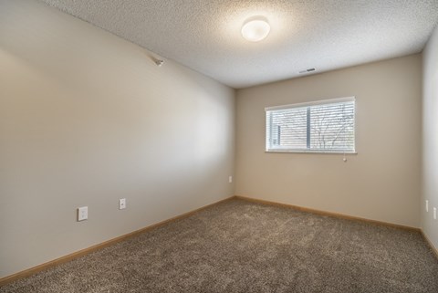 A room with a carpeted floor and a window with blinds.