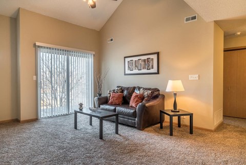 A living room with a grey couch, a small table with a lamp, and a framed picture on the wall.