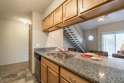 A kitchen with granite countertops and wooden cabinets.