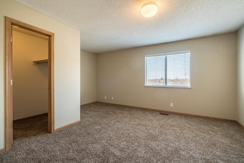 A room with a carpeted floor and a window with blinds.