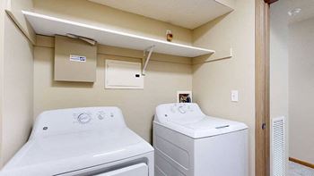 a laundry room with full size washer and dryer and overhead storage