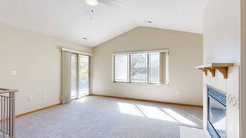 a living room with a large window, a fireplace, and a door to a balcony