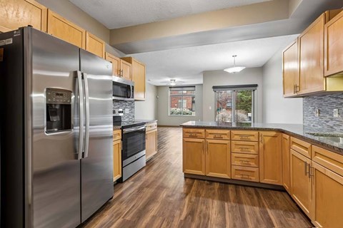 A kitchen with wooden cabinets and a stainless steel refrigerator.