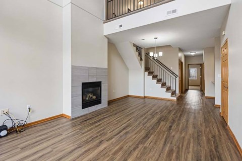 A spacious living room with a fireplace and a staircase.