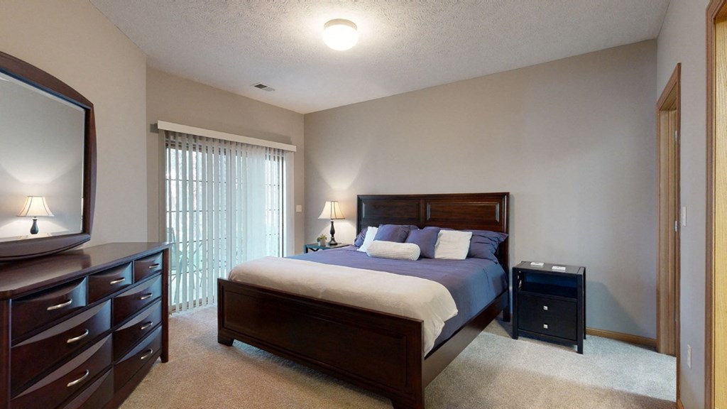 a bedroom with a bed and a dresser with large mirror on top