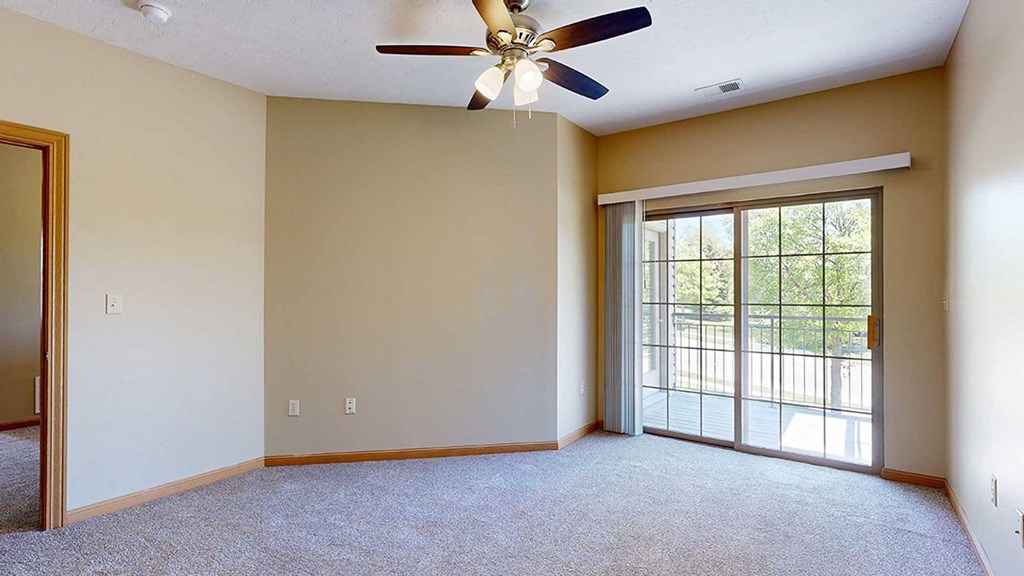 a bedroom with a ceiling fan and sliding glass door to a balcony