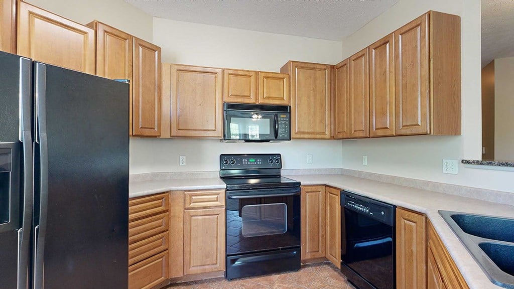 a kitchen with warm wooden cabinets and black appliances