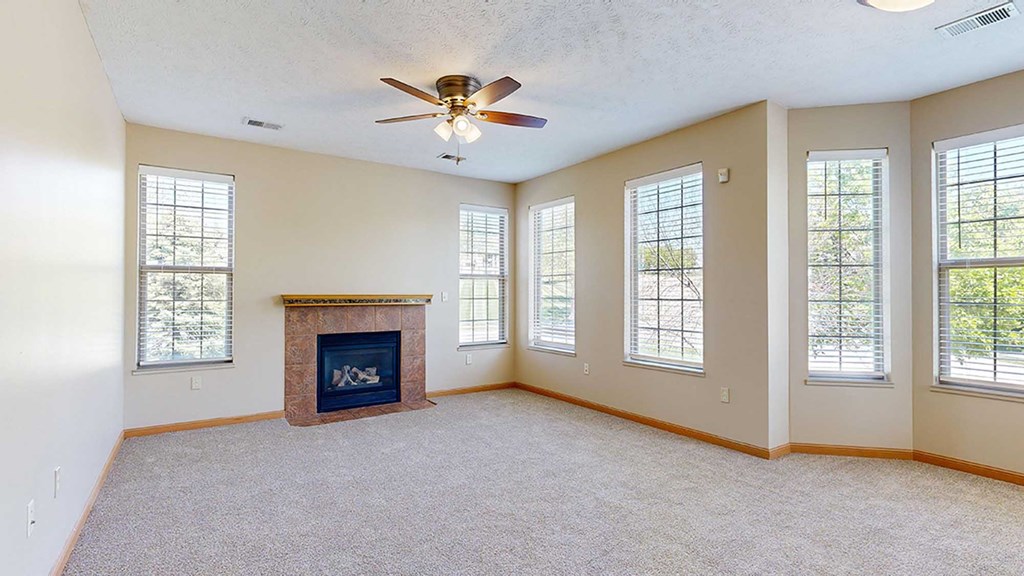 a living room with several windows, a fireplace, and a ceiling fan