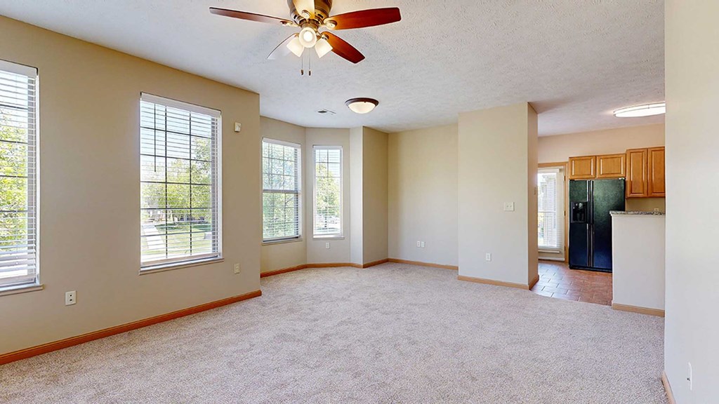 a living room with a ceiling fan adjacent to a dining space and kitchen