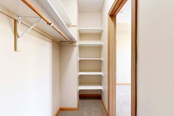 A walk-in closet with several built-in shelves and a long overhead shelf and hanging space.