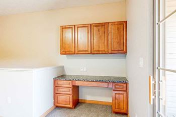 A built-in desk with wooden cabinets and a granite counter in the living room.