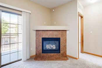 A living room with a fireplace next to the sliding glass door to the balcony.
