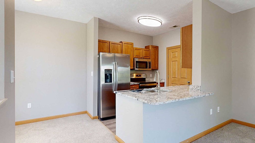 a kitchen with a granite counter top and a stainless steel refrigerator