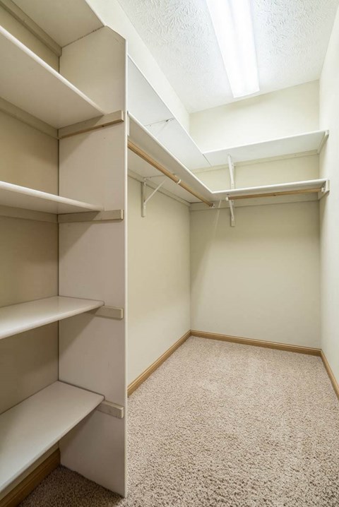 a walk in closet with empty shelves