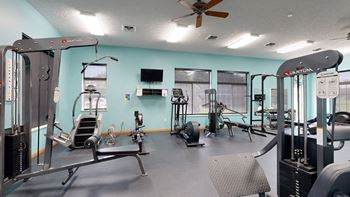 24 hour fitness center with exercise equipment and a flat screen tv