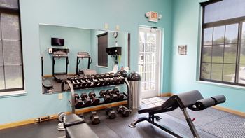 24 hour fitness center with cardio equipment and a large mirror