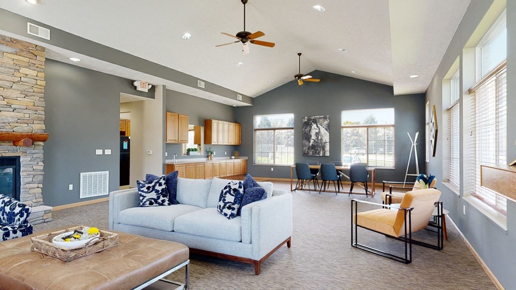 the clubhouse living room with gray walls, a stone fireplace, and seating