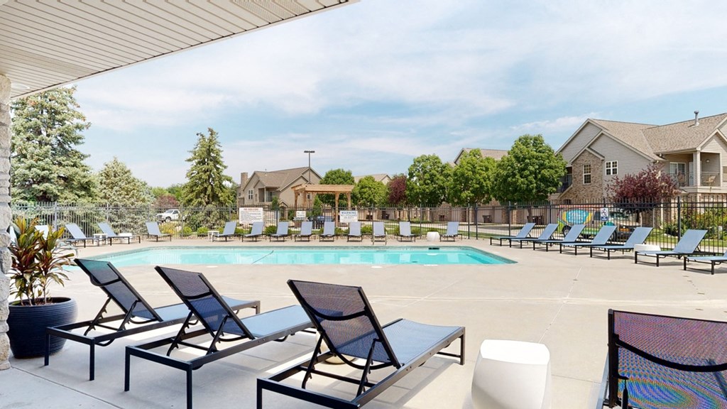 a swimming pool with chaise lounge chairs and trees in the background