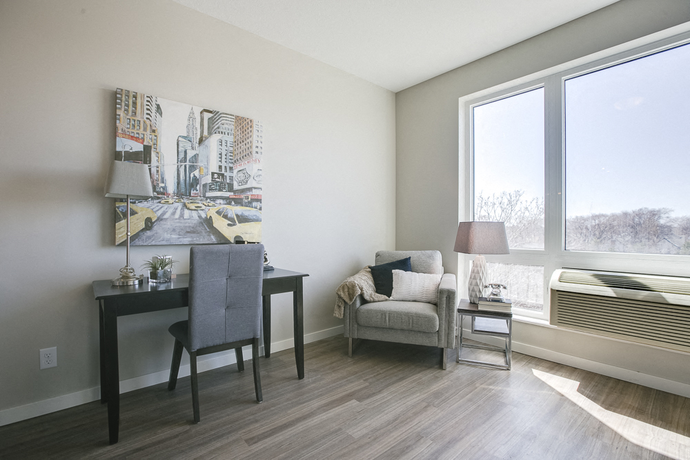 a living room with a desk and a chair and a window