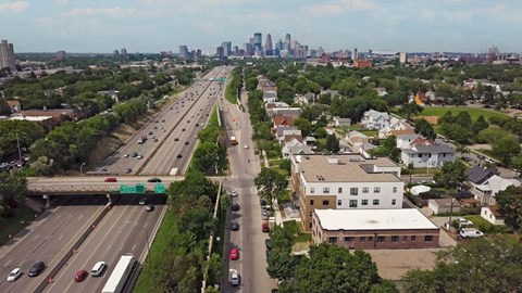 A highway with cars and buildings on the side.