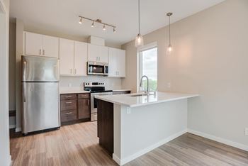 A kitchen with a refrigerator, microwave, and oven.