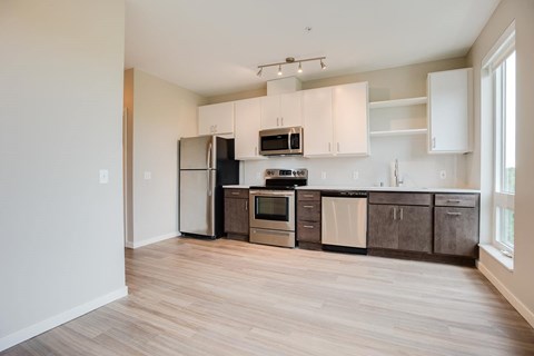 A kitchen with a refrigerator, microwave, oven, and cabinets.