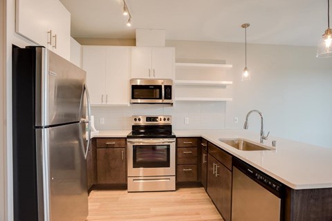 A modern kitchen with a stainless steel refrigerator and a stove top oven.