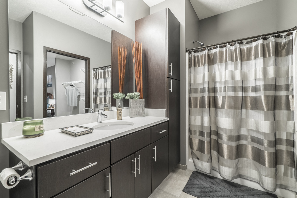 Bathroom with dark cabinetry and quartz countertops at The Conrad in midtown Omaha NE