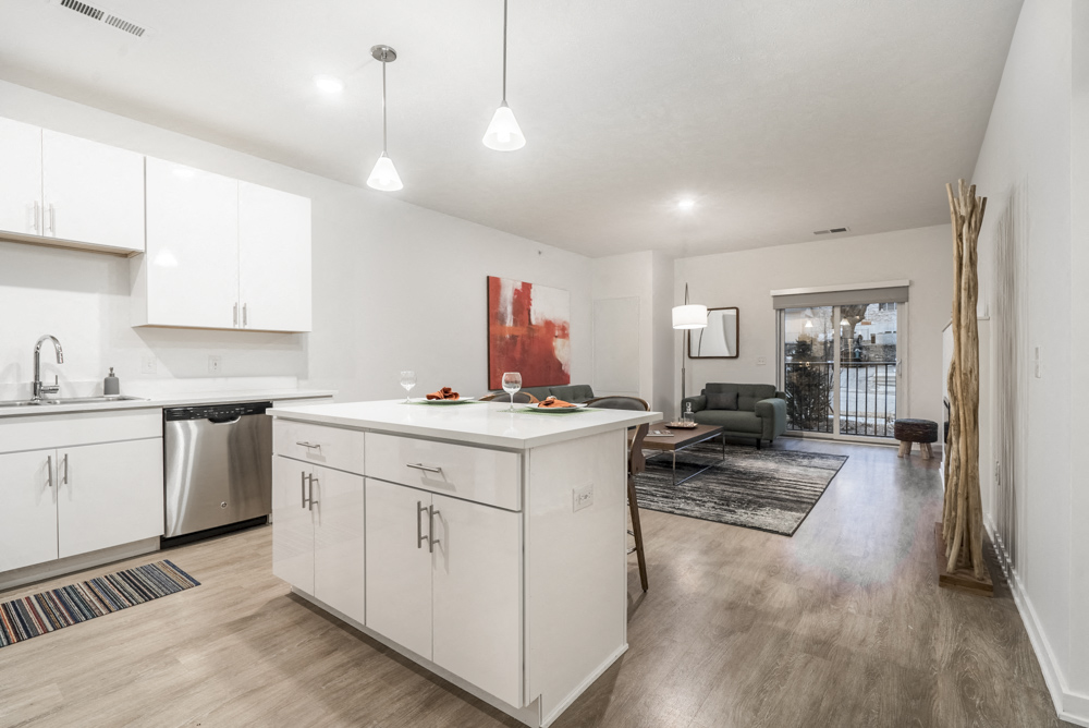 Contemporary design scheme with white kitchen cabinetry, quartz countertops and open layout at The Conrad
