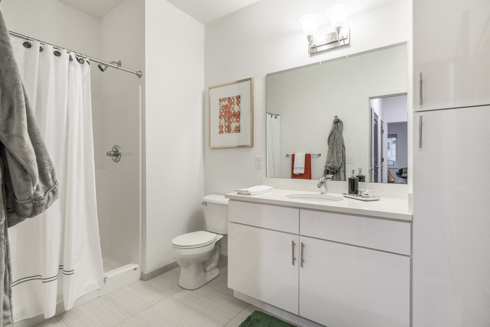 Contemporary bathroom with white cabinetry and white quartz countertops at The Conrad