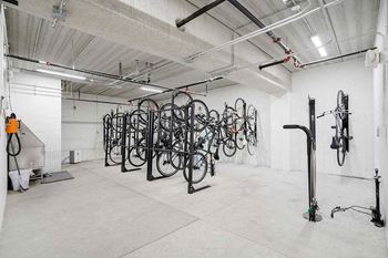 a bike locker room with a tire air pump, multiple bike mounts, and a pet wash station