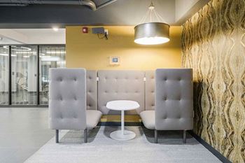 a modern cushioned booth with a  central table and walls for privacy