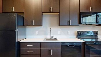 a kitchen with dark brown cabinets and black appliances
