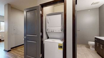 a laundry closet with a stackable full sized washer and dryer