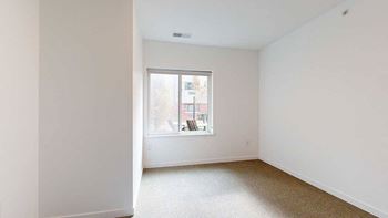 a bedroom with a large window looking out to the courtyard and carpet flooring