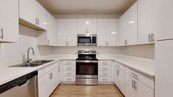 a modern kitchen with white cabinets and stainless steel appliances