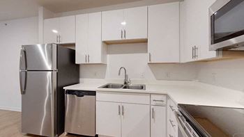 a kitchen with white cabinets and a stainless steel refrigerator next to a stainless steel sink
