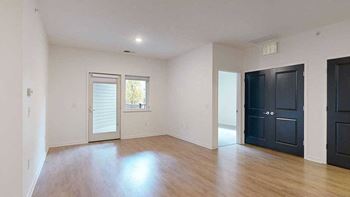 a living room with balcony access and doors to a bedroom and the laundry room