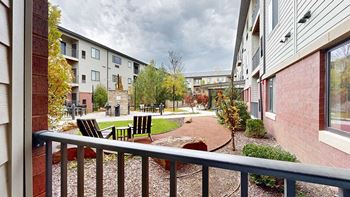 a patio that overlooks a courtyard with a table and chairs and walking path