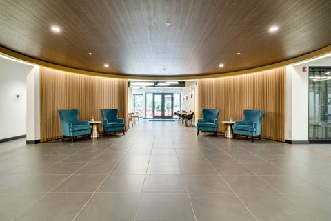 An open apartment lobby with blue chairs and a wooden ceiling.