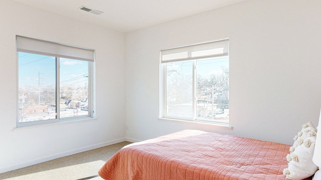 Furnished apartment bedroom with a large window on each wall