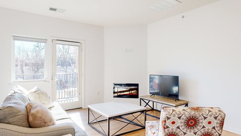 A living room with a couch, a coffee table, fireplace, and a television.
