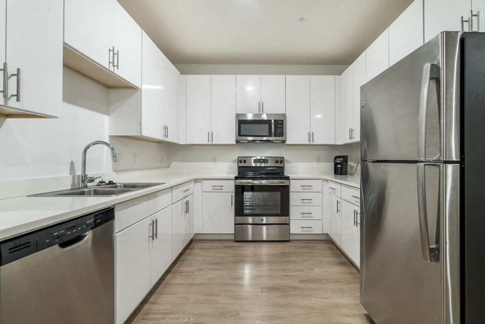 Contemporary kitchen with white cabinetry, quartz countertops and stainless steel appliances at The Conrad