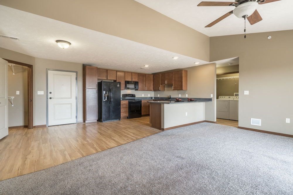A spacious kitchen with wooden floors and a ceiling fan.