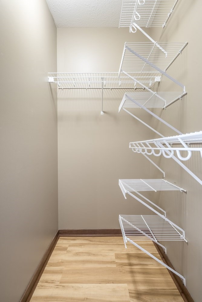 Empty white shelves in a room with wooden floor.