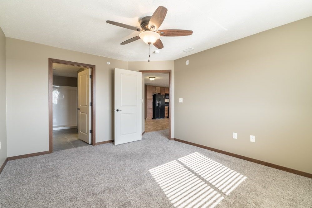 A room with a ceiling fan and carpeted floor.